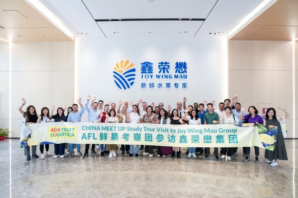 A group of people smile and wave and hold a banner.