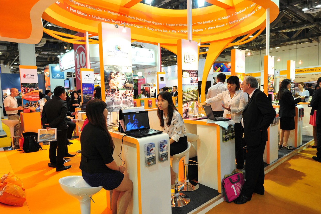 Messebesucher auf einem orangenen-gelben Stand in regen Diskussionen in Asien