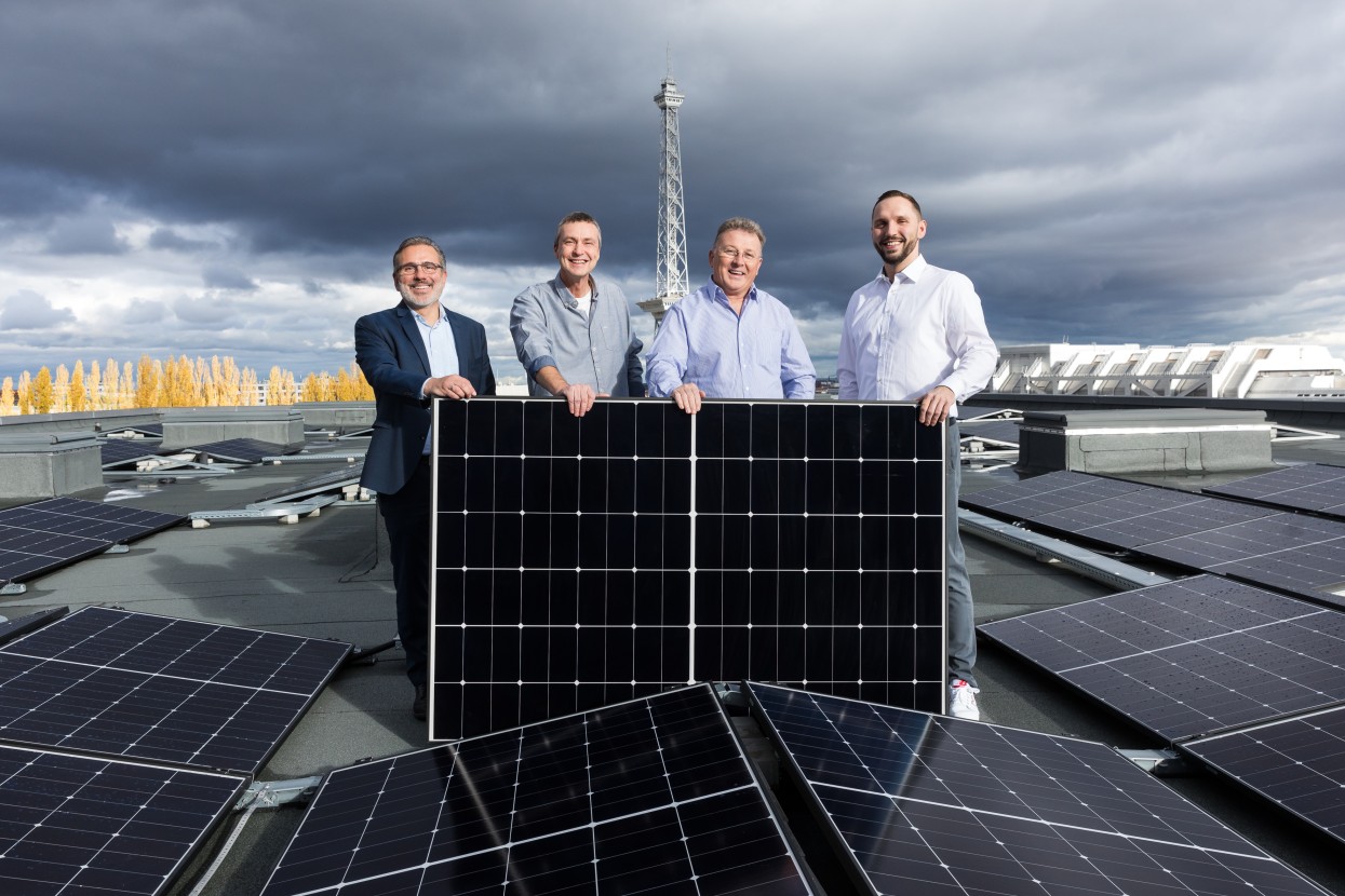 Frank Bro und Team stehen auf dem Messedach und halten ein Solarpanel.